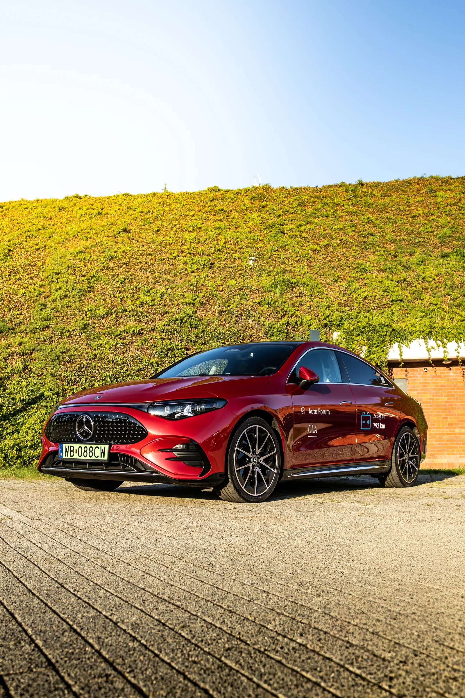 Czerwony Mercedes-Benz CLA przy zielonej ścianie