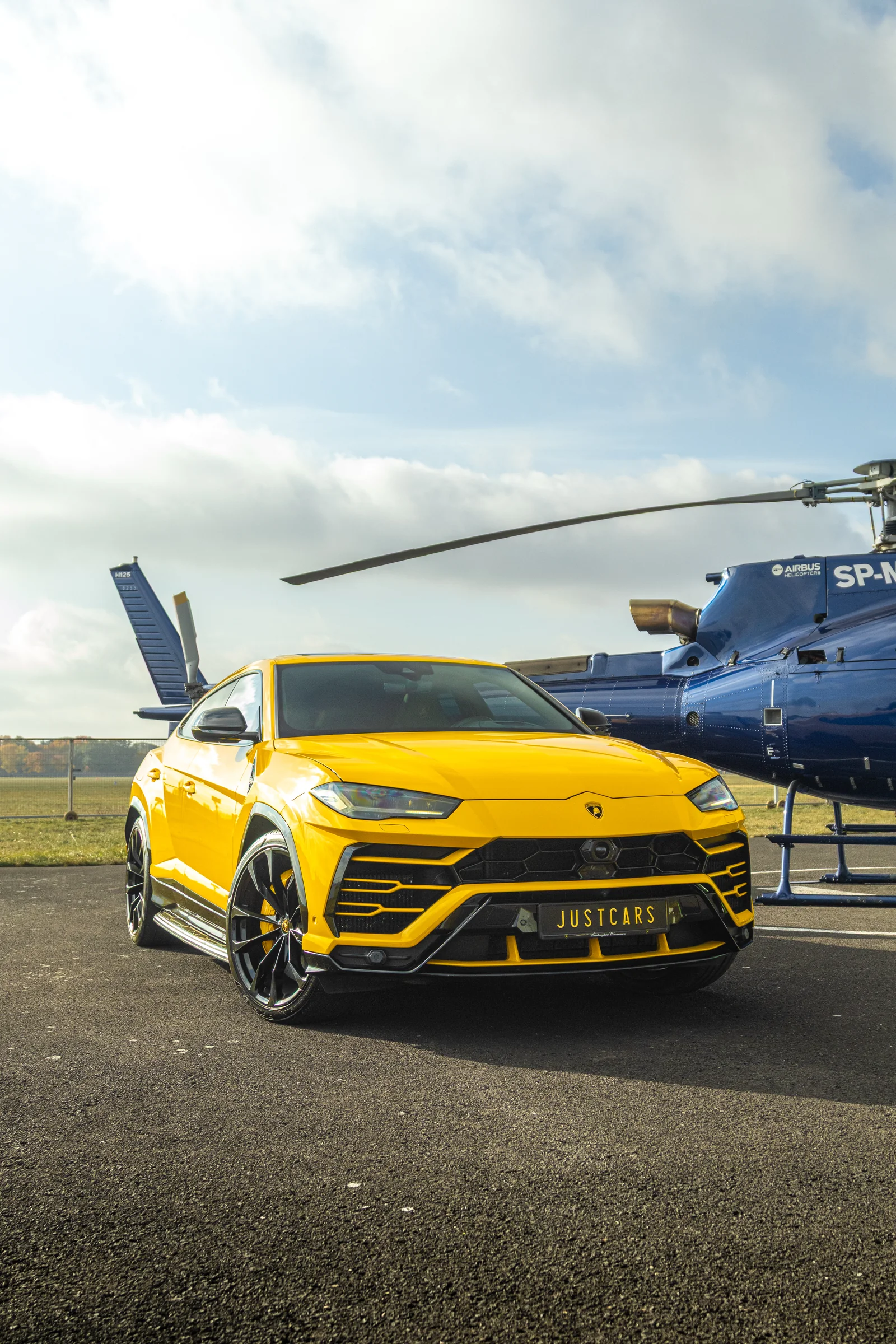 Żółte Lamborghini Urus przy helikopterze